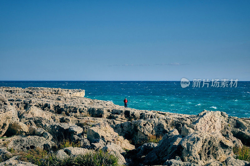 一个孤独的人在岩石上眺望大海