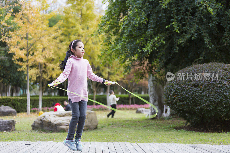 女孩在花园里跳绳。