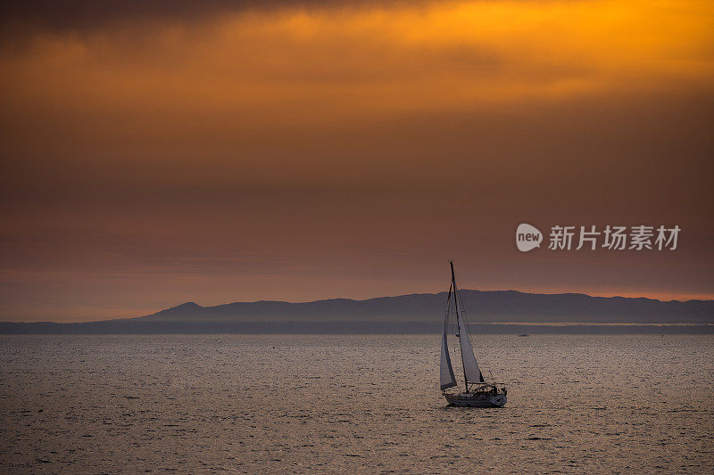 日落时分，一艘游艇在平静的海面上驶向卡特琳娜岛