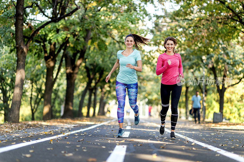 两个女性朋友在阳光公园的小路上慢跑