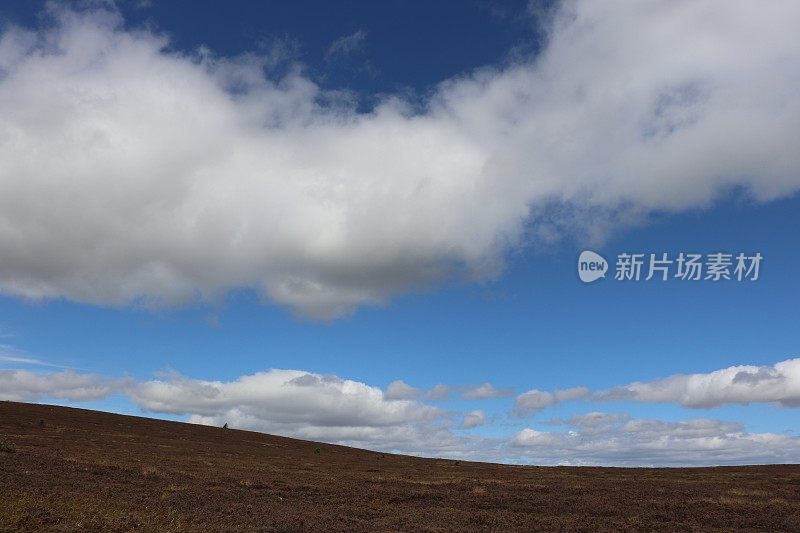 山顶上蓝色的天空中飘浮着白云