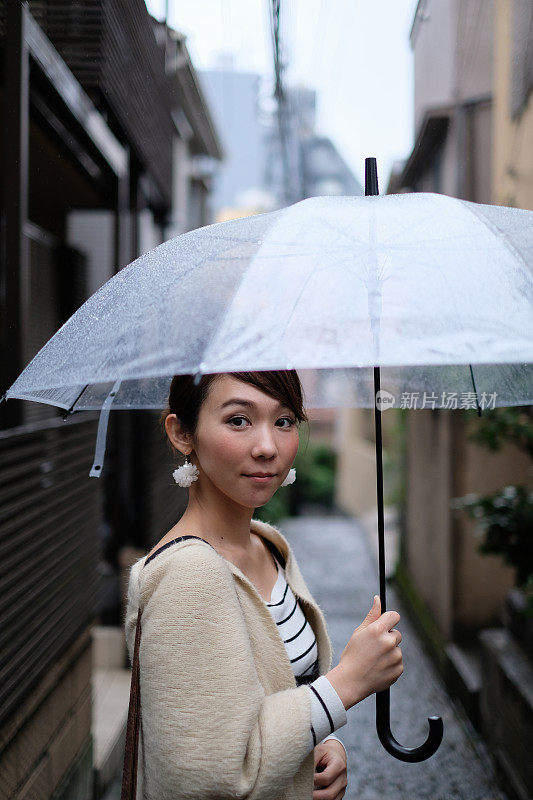 一名妇女走在东京神乐坂传统老城的小巷里，在一个雨天