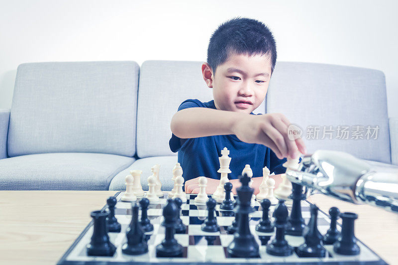 聪明的男孩在室内与机器人下棋