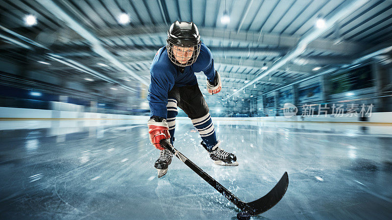 年轻的曲棍球运动员准备在冰上竞技场的背景下做一个强有力的射击