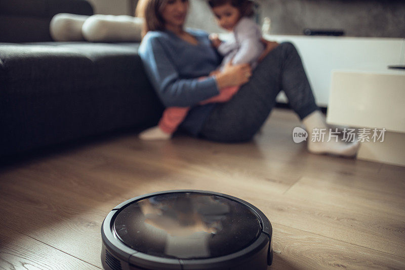 妈妈和女儿放松的时候，机器人真空吸尘器打扫地板