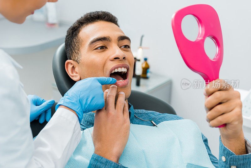 女牙医摸着英俊的非裔美国人的牙齿