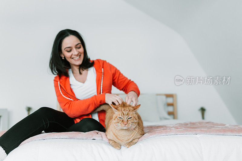 一个年轻女人和她的猫在床上