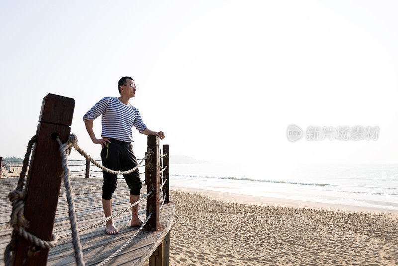 靠在海滩栏杆上的男人