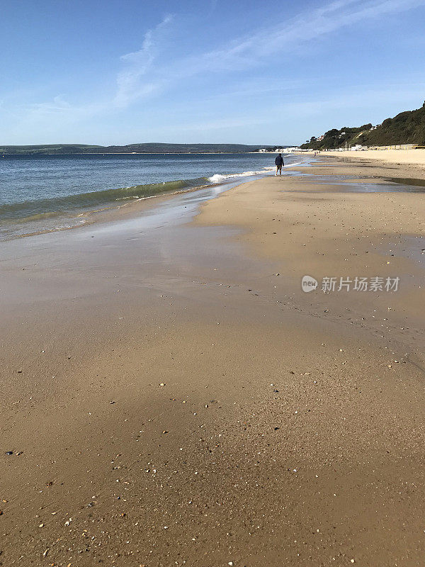 金色的沙滩，大海和阳光明媚的蓝天在伯恩茅斯英国海岸线，阿尔姆中国海滩的南部侏罗纪海岸线，伯恩茅斯，多塞特，沙滩上的阳光与海浪拍打海岸和蓝天照片，低潮