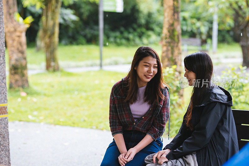 两个漂亮的年轻女子在公园的长椅上休息