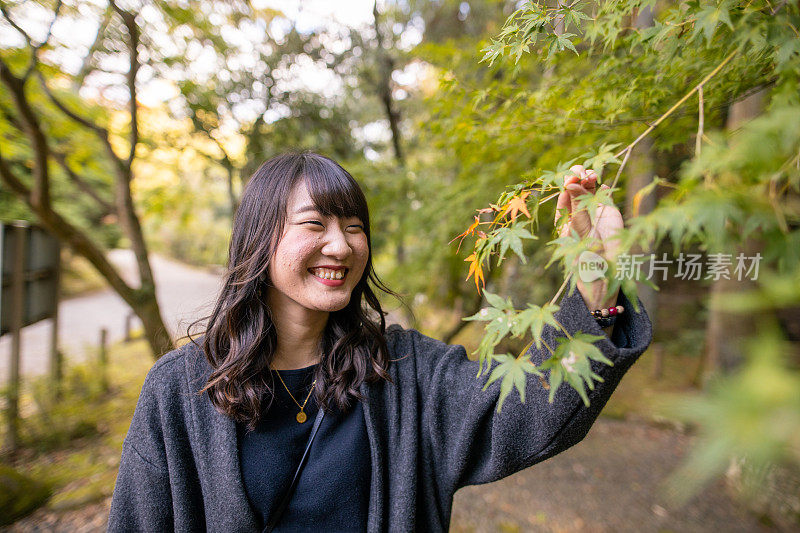 快乐的年轻女子触摸枫叶