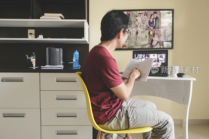 一名男子在家里参加一个视频会议,与在线图书俱乐部的成员一起阅读