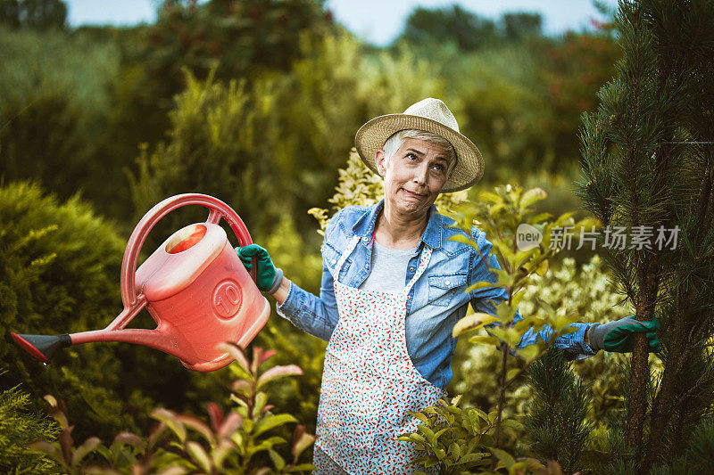 一个成熟的女人在后院浇水时做着鬼脸。