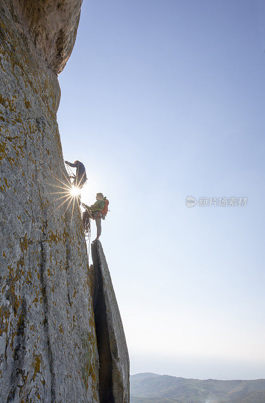 登山者在日出时攀登岩面