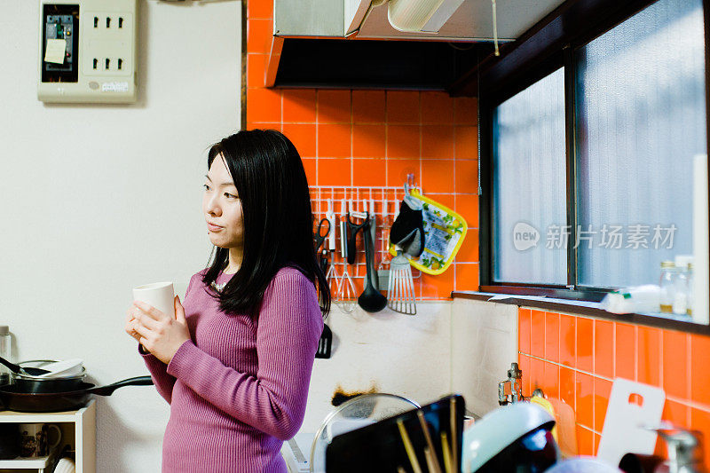 亚洲妇女在厨房喝咖啡休息的照片
