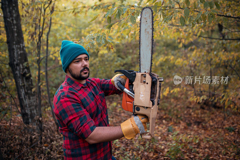 在森林里手持电锯的年轻伐木工
