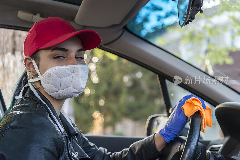 一位年轻女子正在用消毒剂给她的汽车仪表盘消毒