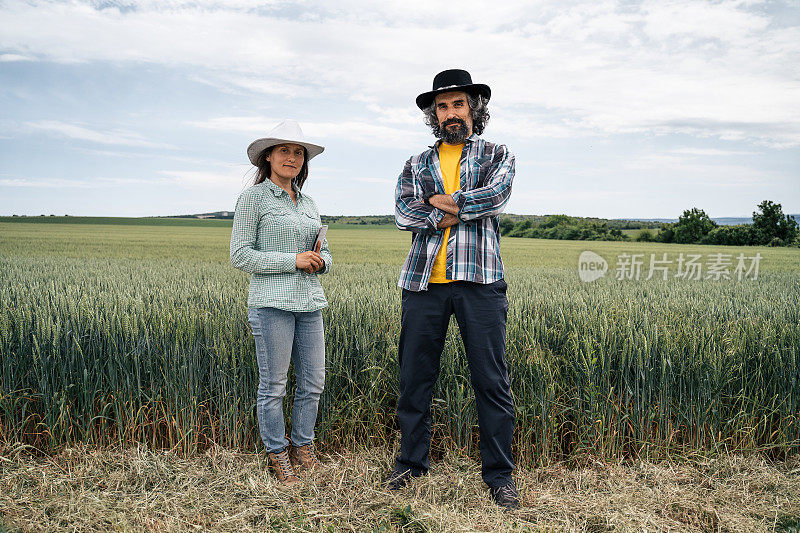 一个农民的家庭站在麦田中间，微笑着看着镜头。农业职业。家族企业。