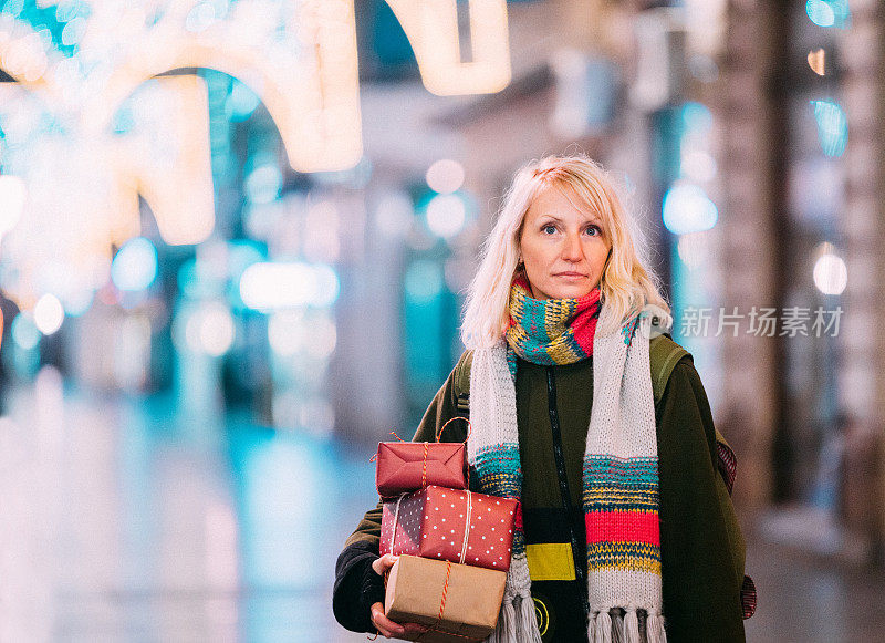 一个年轻的女人购物圣诞和新年礼物在城市