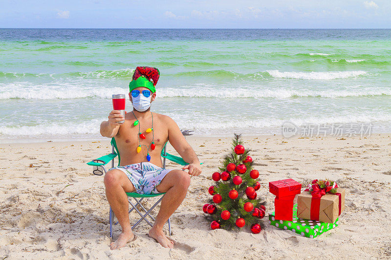 美国佛罗里达州迈阿密海滩，一名戴口罩的年轻男子在冠状病毒Covid-19大流行疾病中崩溃，正在玩，喝着啤酒
