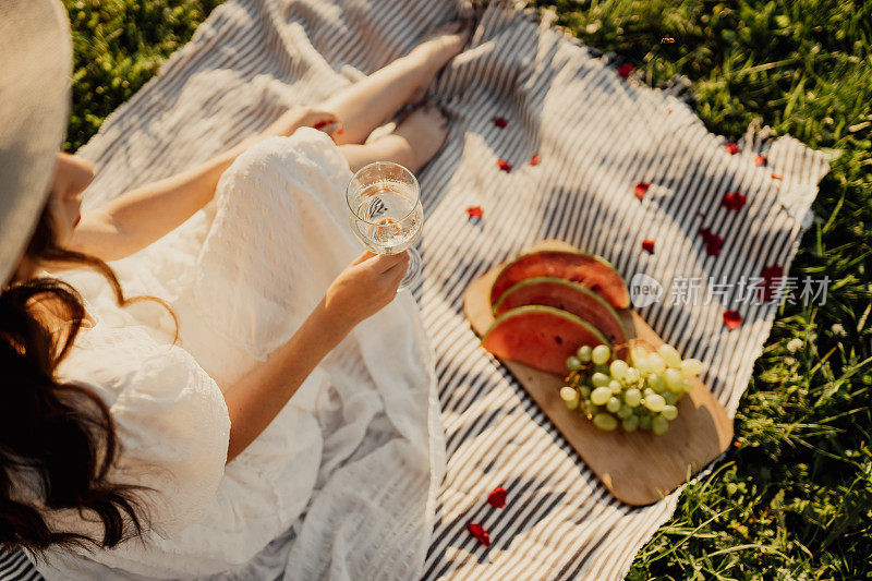 夏日野餐，女人手里拿着酒和开胃菜盘