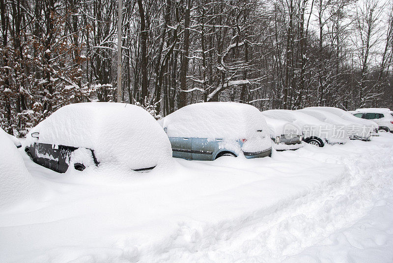 白雪覆盖的街道，道路和汽车在雪下。暴风雪，暴风雪交通。天气气候灾难。冬天的城市风光。雪后的雪堆