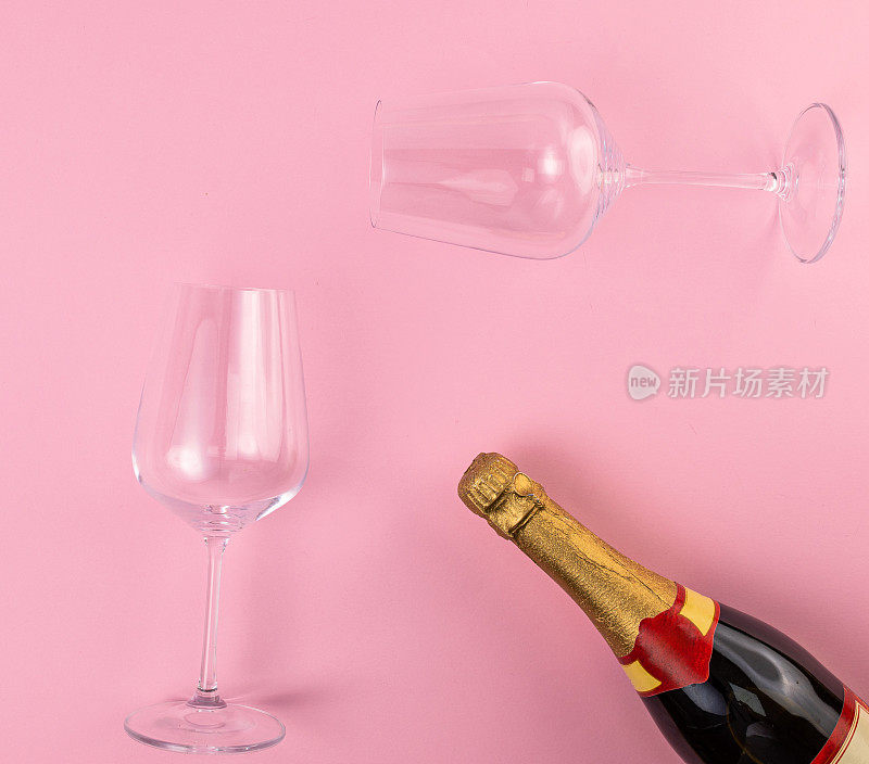 粉红背景上的酒杯和香槟瓶