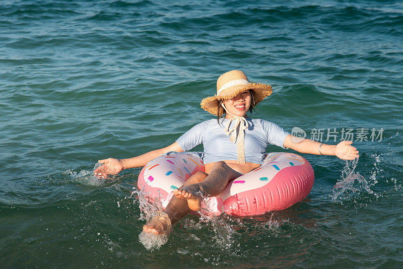 女人游泳和漂浮在海边的水与甜甜圈浮