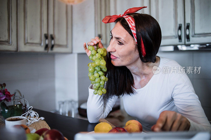 健康成熟的女人早餐吃健康食品——水果