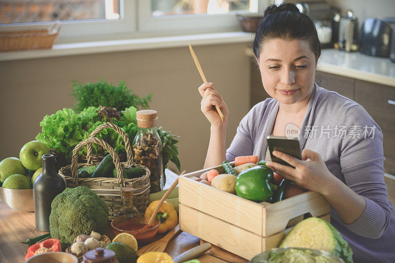 在厨房里做饭的女人(带着智能手机)