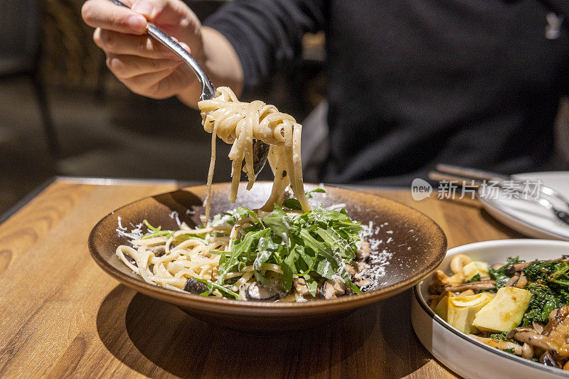 人们在素食餐厅吃蔬菜奶油意面