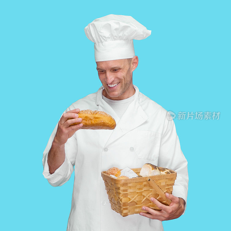 白人年轻男性面包师，穿着裤子，拿着法棍面包站在蓝色背景前