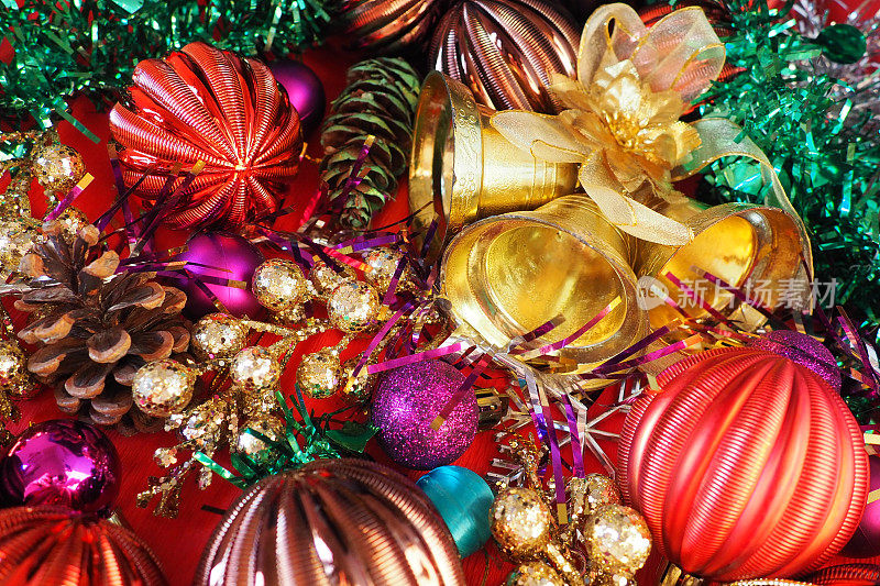 圣诞节背景有圣诞装饰品，节日球，铃铛，蝴蝶结，冷杉锥，圣诞树雨。新年快乐，圣诞快乐。红色，棕色，条纹，绿色，金色，紫色，五颜六色的装饰
