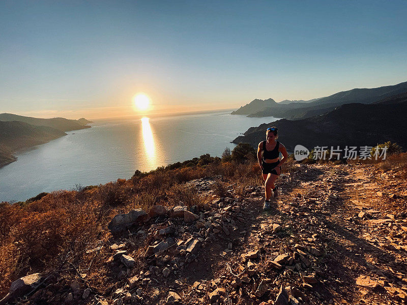 清晨，年轻女子在海边的山坡上奔跑