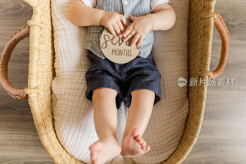 7个月大的男婴，有12个脚趾，躺在一个舒适的海草摩西篮子里，白色亚麻布