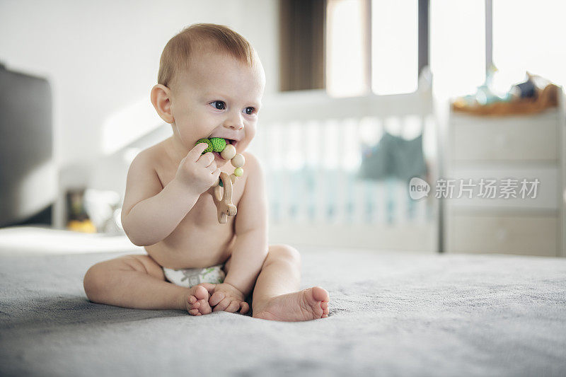 可爱的男婴玩一个木制的出牙玩具。