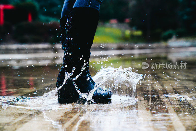 穿着雨靴在深水坑里跳