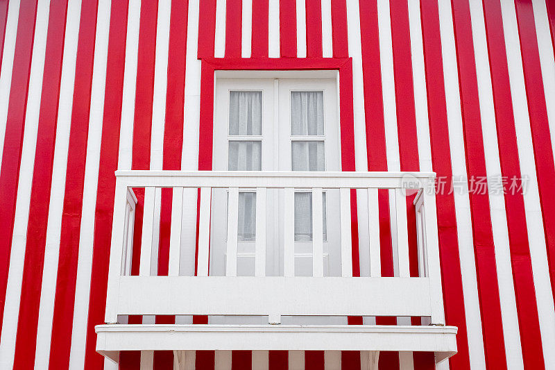 老木门和阳台的背景是红白相间的条纹墙。葡萄牙的窗户。葡萄牙房屋的外观