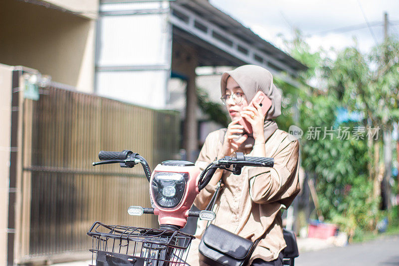 年轻的伊斯兰妇女在居民区骑电动自行车