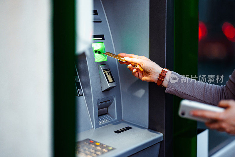 近距离照片，女子双手将信用卡放入自动取款机