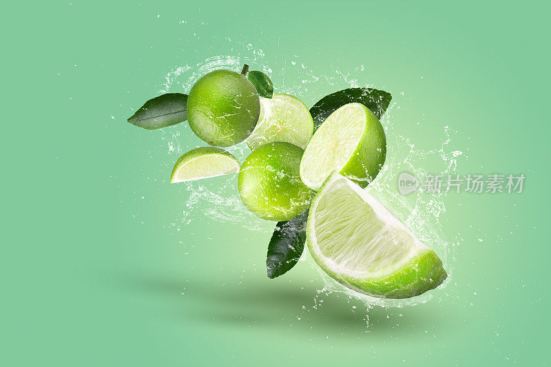 创意布局由青柠水果和青柠片和水溅在绿色背景。
