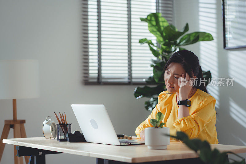 亚洲女性坐在家里头疼。