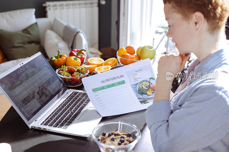 一位女营养师正在为使用笔记本电脑的客户制定饮食计划