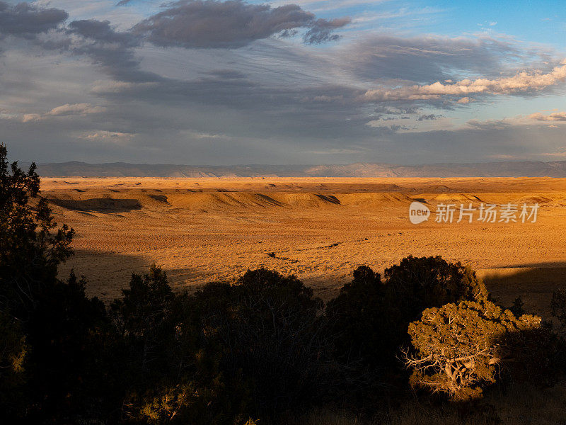 夕阳落在犹他州绿河沙漠的山丘上。