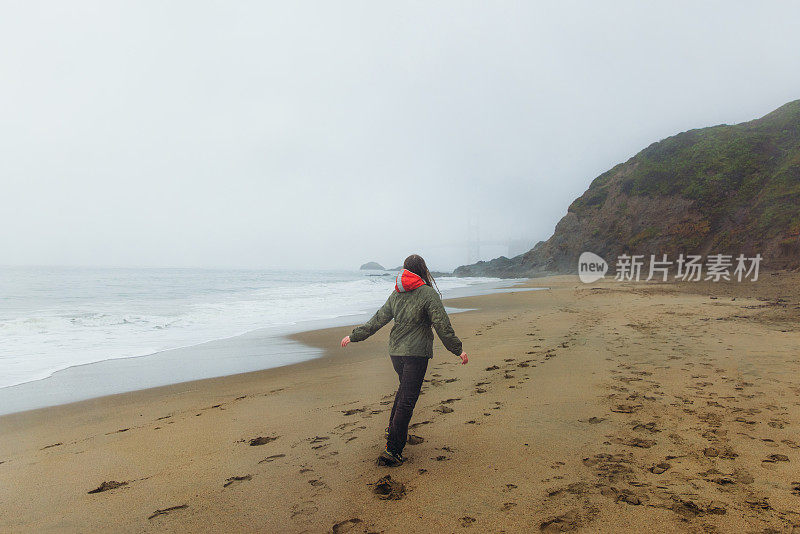 一个快乐的女人在加利福尼亚旧金山的海滩上散步