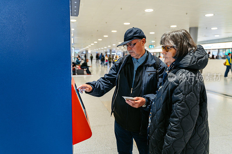 一对老年夫妇在苏黎世火车站用智能手机买火车票