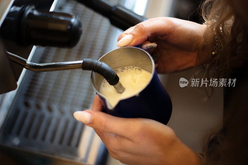 女咖啡师正在煮热牛奶。