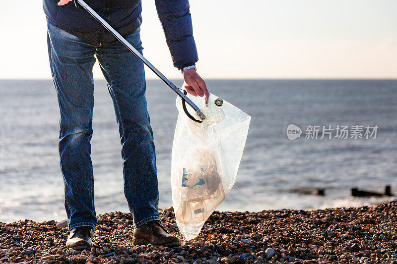 一位老人正在清理海滩上的塑料污染