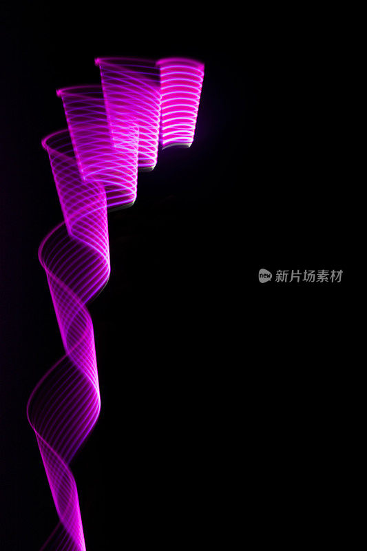 粉红色和紫色辉光的霓虹波卷曲或漩涡与平滑的条纹在黑色的背景，垂直。抽象的背景与流动的线条在运动，光画在蒸汽波风格。