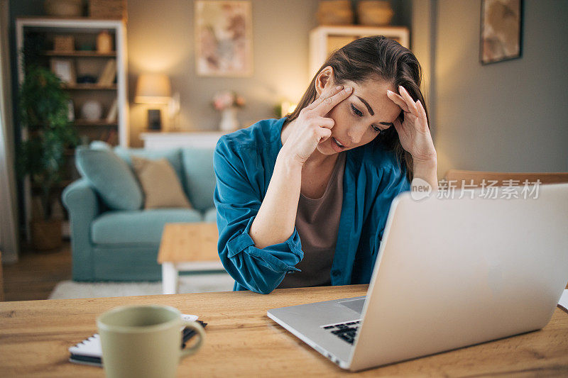 迷人的成年女商人独自坐在家里的办公室里，感觉压力很大